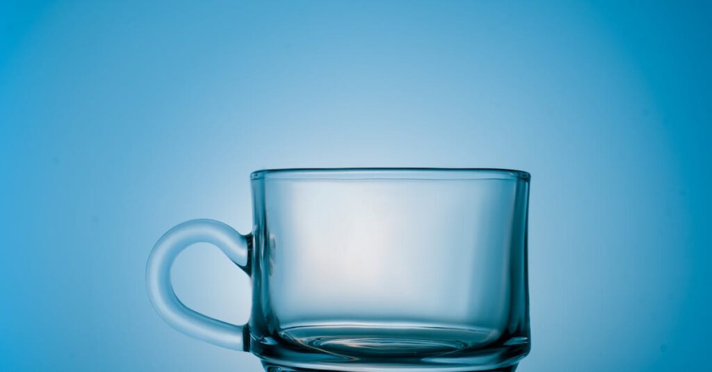A minimalist clear glass mug placed against a blue backdrop, showcasing elegance.