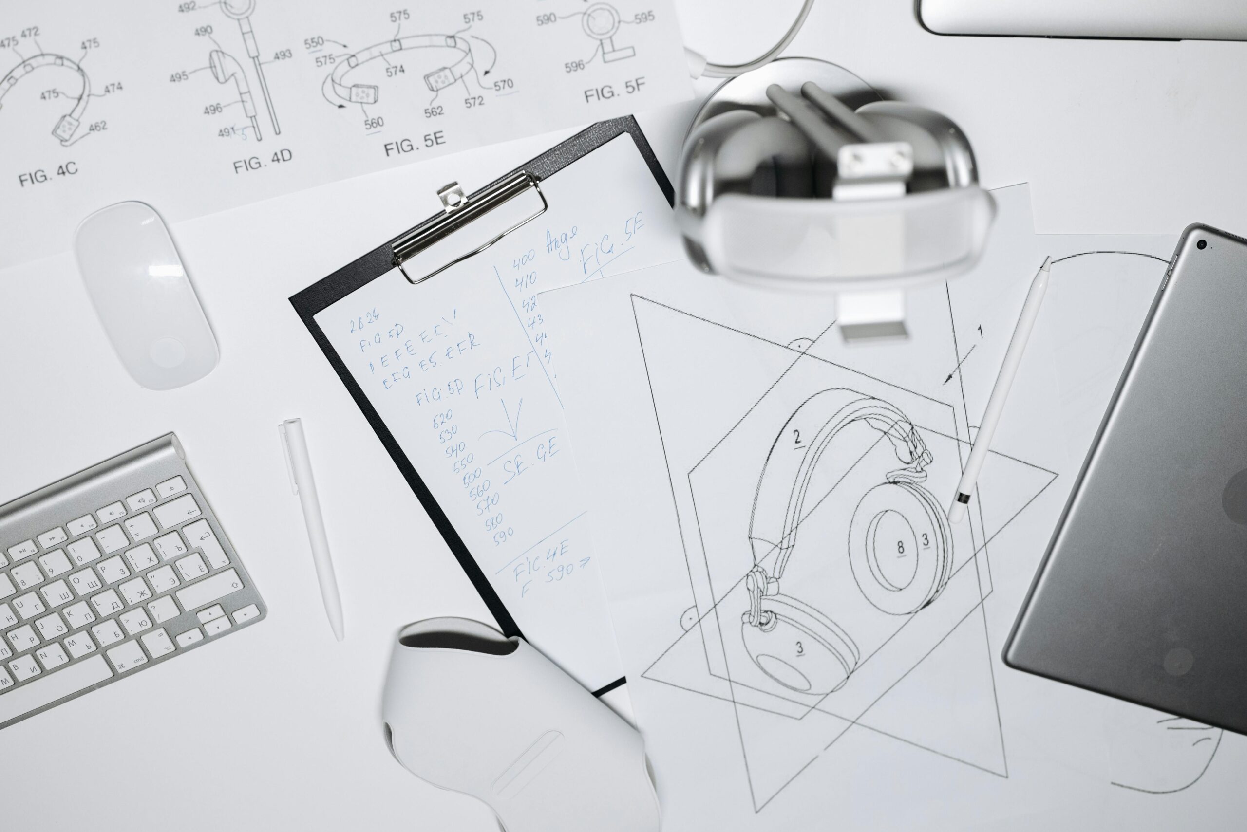 Top view of a workspace with headphone design sketches, keyboard, and mouse.